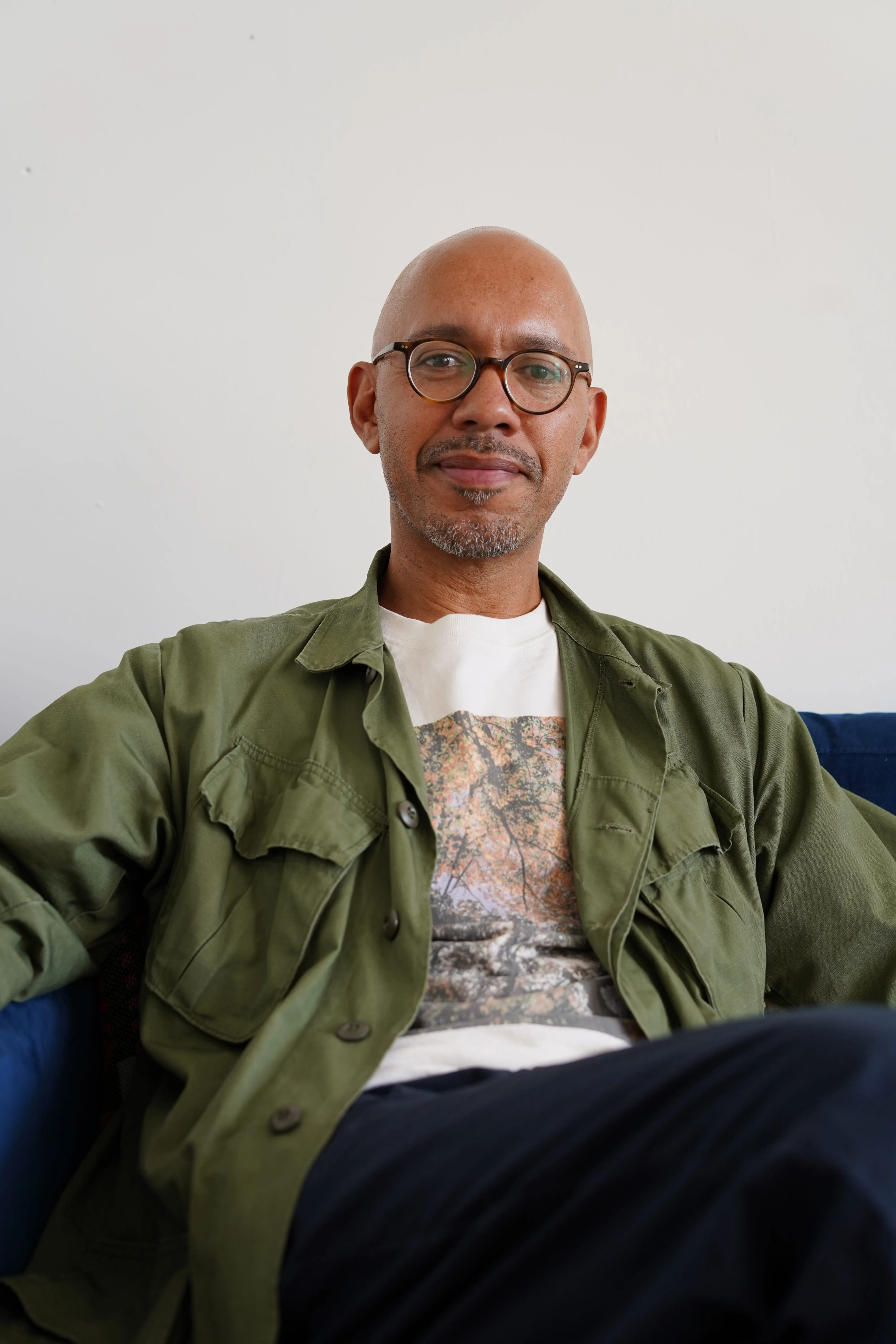 Portrait photo of Paul Camo, sat on a sofa 