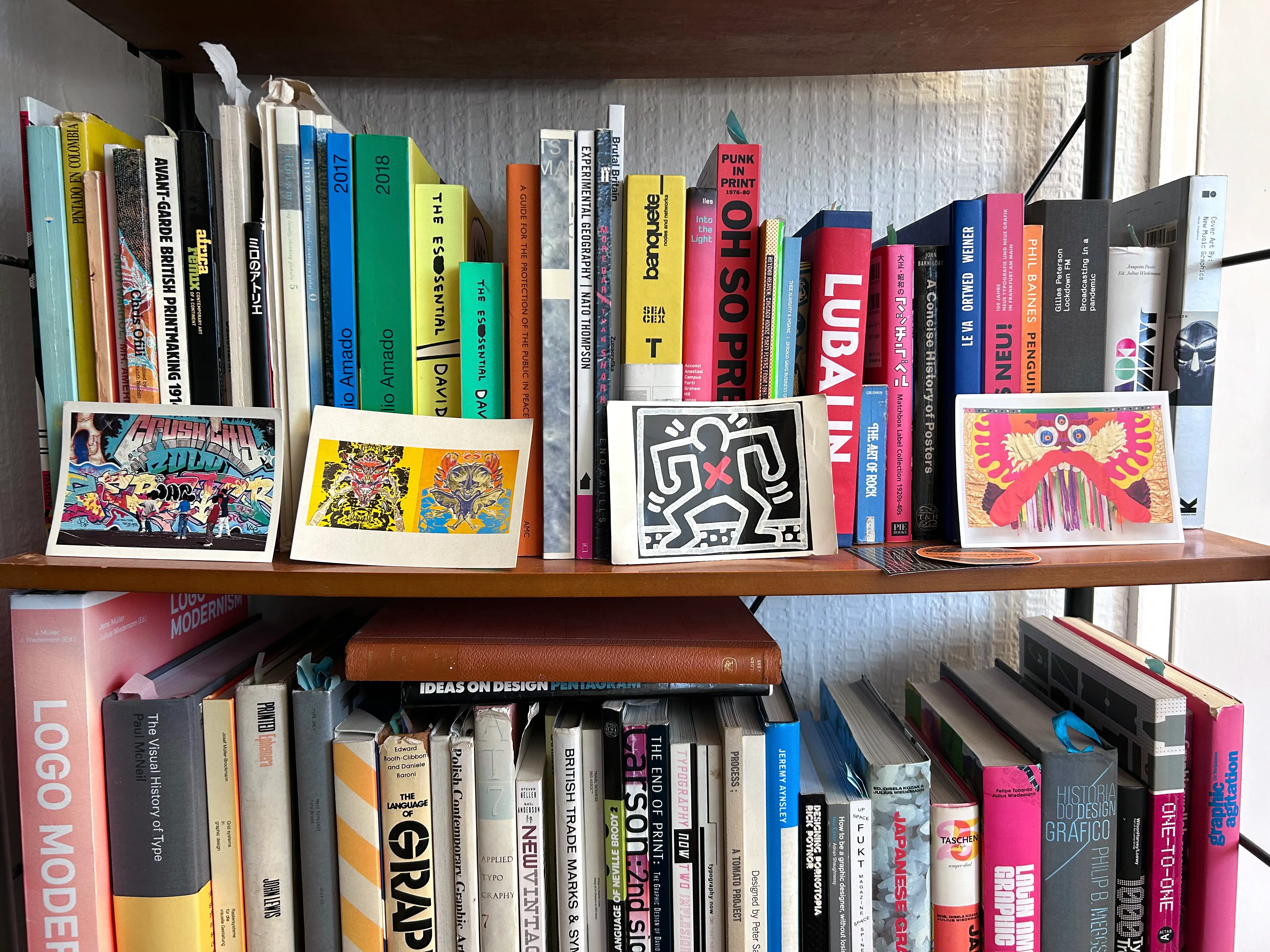 A shelf with a selection of design, culture and wellbeing books and postcards